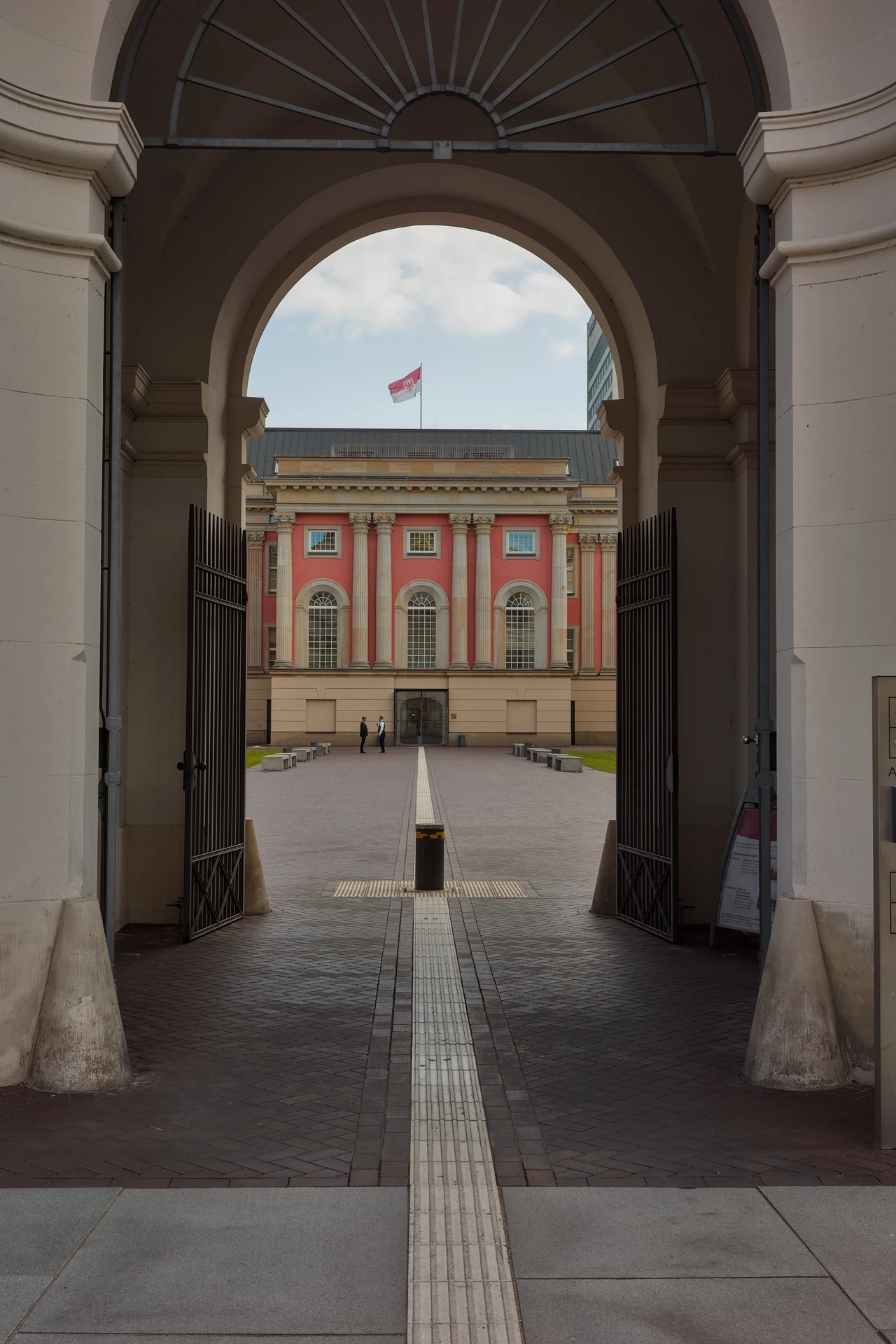 A photo of the Stadschloss Potsdam through the main portal. The flag of the state Brandburg can be ssen.